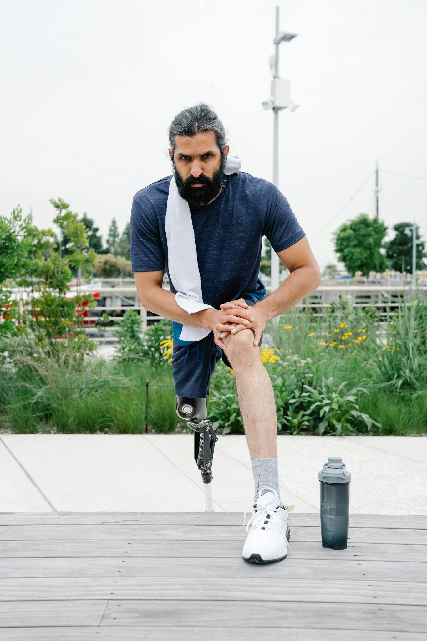 A man with a prosthetic leg stretches outdoors, focusing on fitness and health.